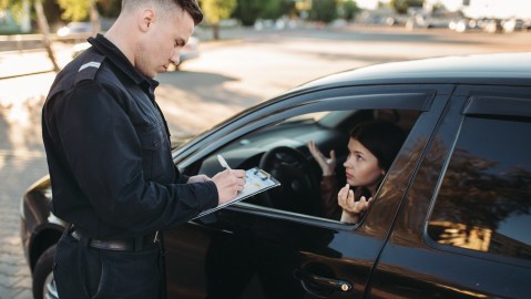 Foto de un oficial de policía imponiendo una multa a una mujer que conduce un vehículo