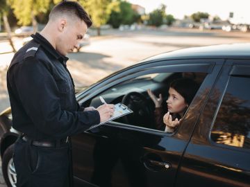 Foto de un oficial de policía imponiendo una multa a una mujer que conduce un vehículo