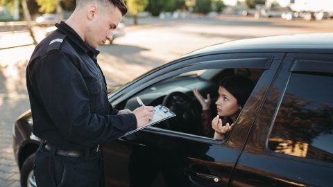 Foto de un oficial de policía imponiendo una multa a una mujer que conduce un vehículo