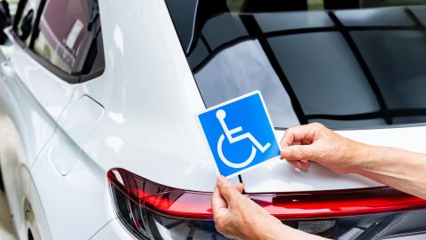 Foto de las manos de una persona sosteniendo un cartel para personas discapacitadas