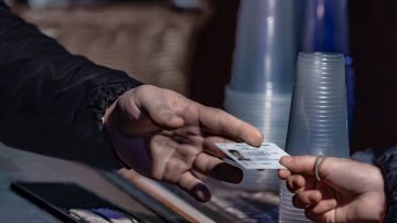 Foto de la mano de una persona entregando su identificación a otra