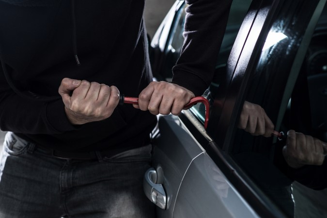 Foto de un ladrón intentando abrir un vehículo.
