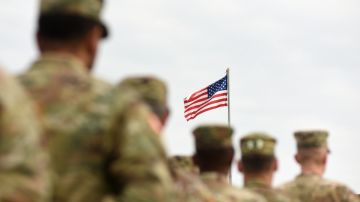 Foto de varios militares en fila junto a la bandera de los Estados Unidos