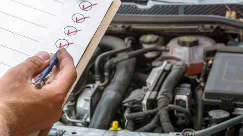 Foto de una persona chequeando el motor de un auto