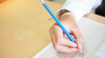 Foto de la mano de una persona presentando un examen escrito