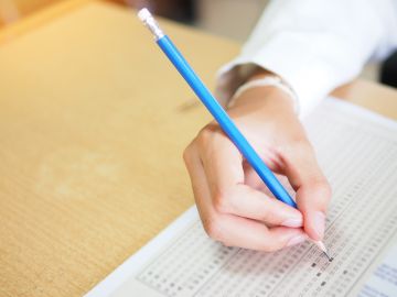 Foto de la mano de una persona presentando un examen escrito