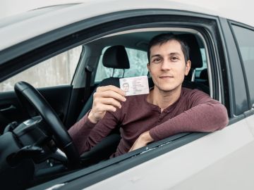 Foto de un hombre mostrando su licencia de conducir desde el auto.