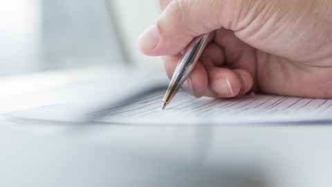 Foto de la mano de una persona completando un formulario