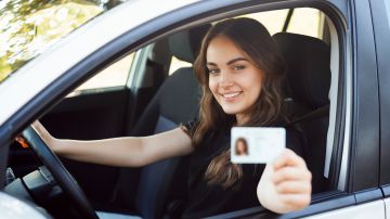 Foto de una mujer mostrando su licencia de conducir mientras conduce.