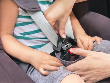 Foto de las manos de una persona sujetando el cinturón de seguridad de un niño