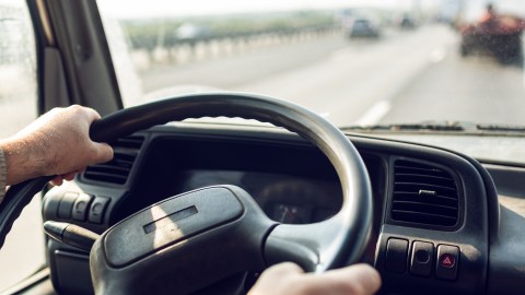 Foto de las manos de una persona sobre el volante de un camión