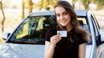 Foto de una mujer sonriente sosteniendo una licencia de conducir