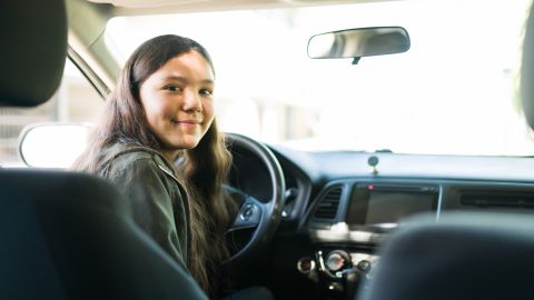Foto de una adolescente frente al volante de un vehículo