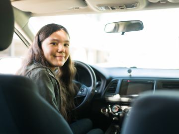 Foto de una adolescente frente al volante de un vehículo