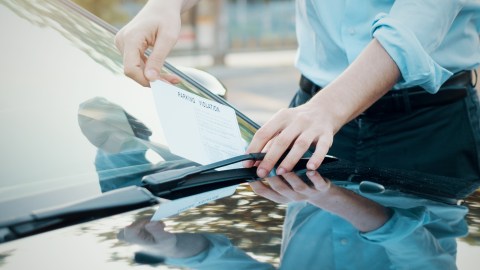 Un hombre recoge una multa de tránsito de su parabrisas.