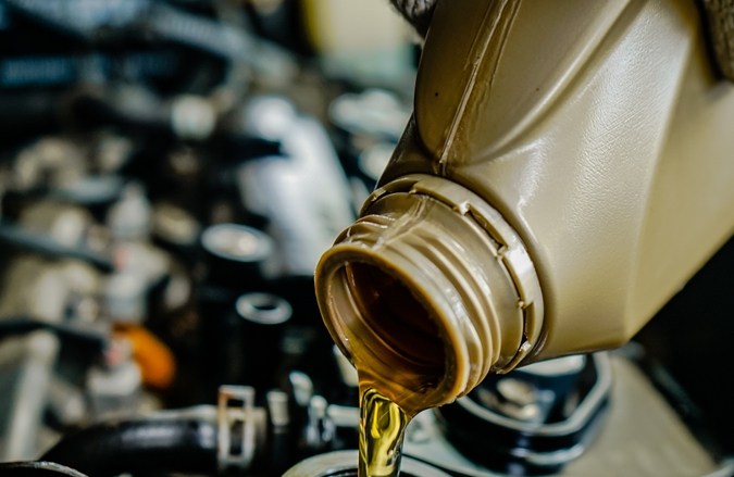 Hombre que vierte el aceite de motor en el motor del coche.