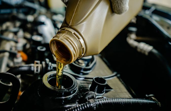 Hombre que vierte el aceite de motor en el motor del coche.