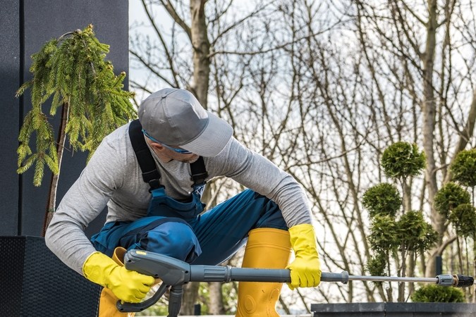 Hombre lavando a presión la parte inferior de su auto