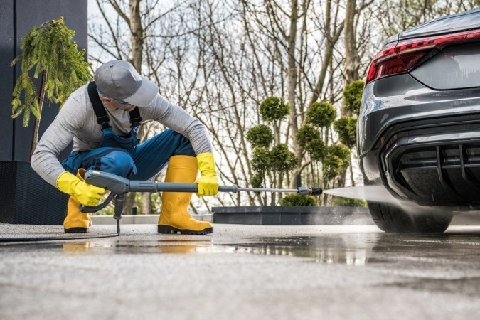 Hombre lavando a presión la parte inferior de su auto