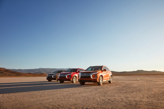 Familia Mitsubishi Outlander Sport 2025, mostrando los 3 modelos disponibles en color negro, rojo y naranja en el desierto