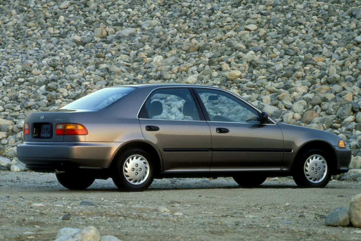 Honda Civic 1993, diseño clásico, paisaje montañoso, sedán plateado, carretera despejada.