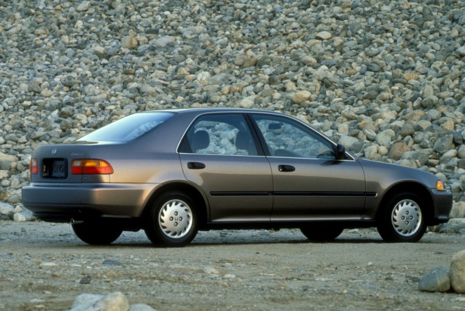 Honda Civic 1993, diseño clásico, paisaje montañoso, sedán plateado, carretera despejada.