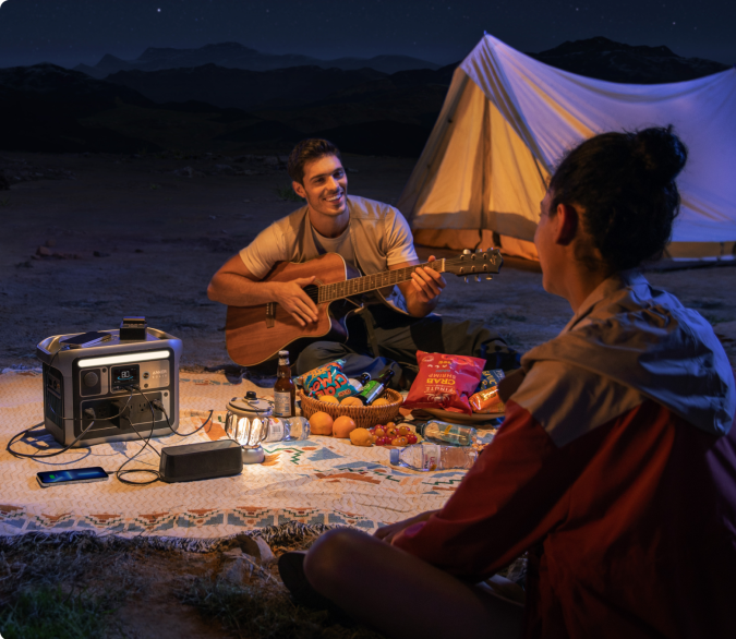Personas acampando en la noche con un generador Anker Solix C1000 sobre la cobija del picnic
