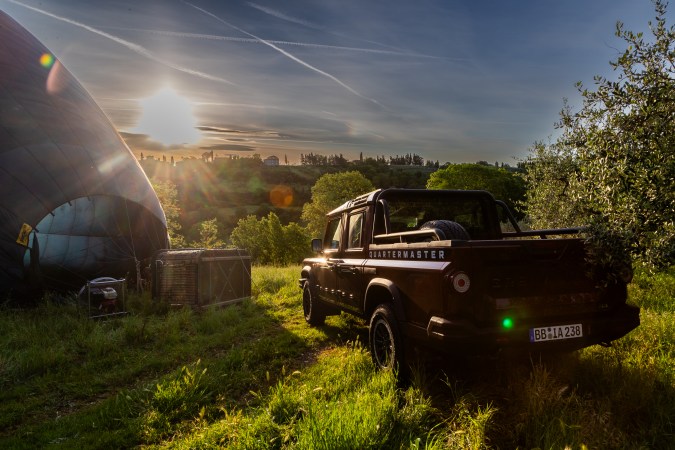 Ineos Grenadier Quartermaster pick-up negra en campo con el sol de fondo