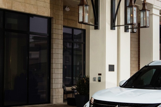 SUV blanco de Mitsubishi, modelo Outlander estacionado frente a un edificio elegante, mostrando su parrilla frontal distintiva y diseño urbano.