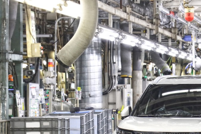 Mitsubishi Outlander, SUV blanco en una línea de ensamblaje de fábrica, con maquinaria y equipo industrial al fondo.