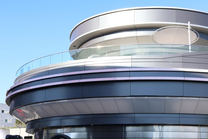 Vista exterior de una tienda Tesla con varios vehículos Tesla, incluyendo un Model 3 rojo, un Model X blanco y un Cybertruck, estacionados frente a la entrada.