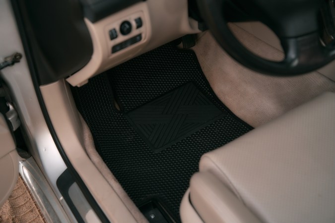 Coche de lujo con decoración de cuero blanco con alfombras de suelo EVA de alta calidad en color negro. Cierre de la alfombra negra del suelo del coche de acetato de etileno.