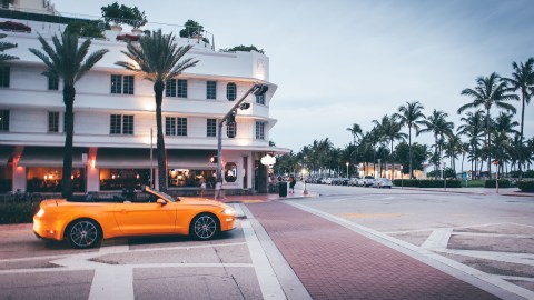 Auto muscle car amarillo convertible girando a Ocean drive en miami beach al atardecer