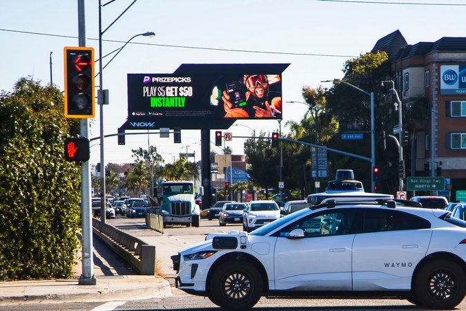 Un coche autónomo Waymo espera en una intersección concurrida.