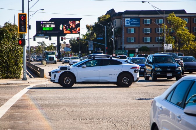 Un coche autónomo Waymo espera en una intersección concurrida.