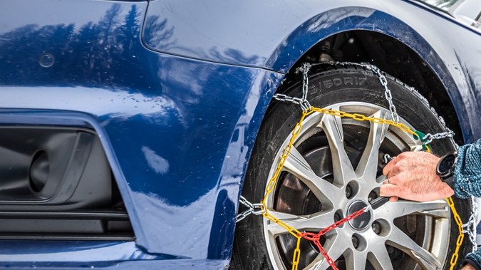 Poniendo cadenas de nieve en la rueda delantera del eje conductor.