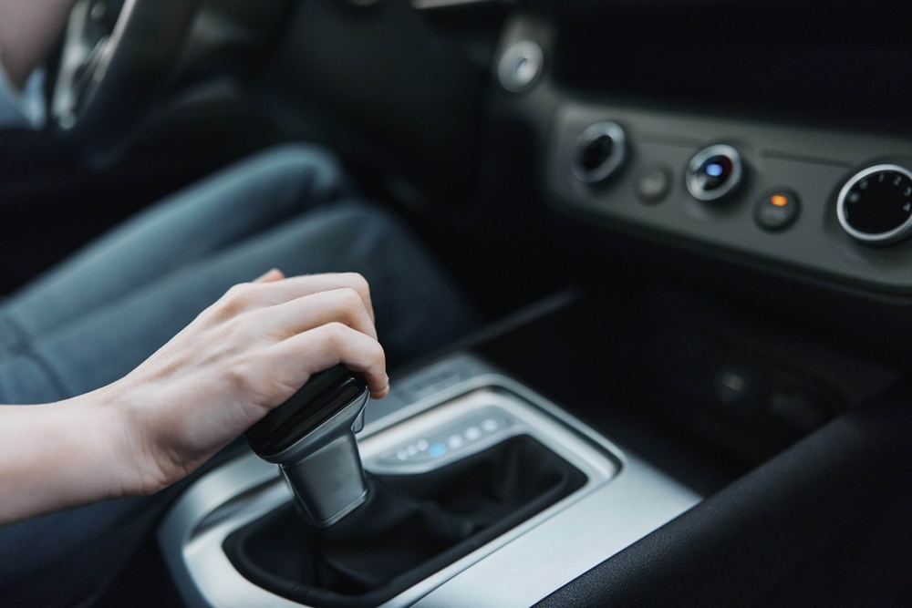 Mano ajustando palanca de cambios en carro automático, destacando manejo seguro y uso adecuado.