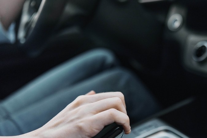 Mano ajustando palanca de cambios en carro automático, destacando manejo seguro y uso adecuado.