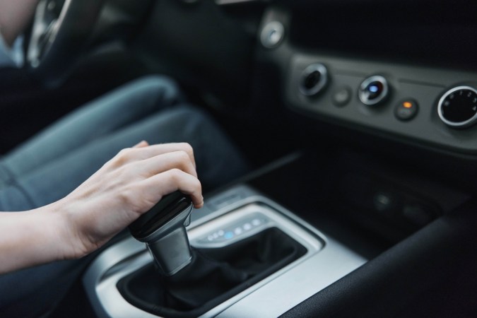 Mano ajustando palanca de cambios en carro automático, destacando manejo seguro y uso adecuado.