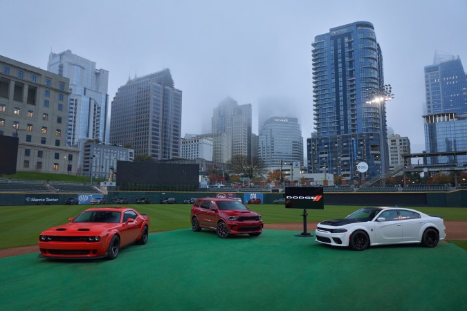Gama Dodge SRT compuesta por un Challenger, un Durango y un Charger exhibidos en un estadio con rascacielos de fondo