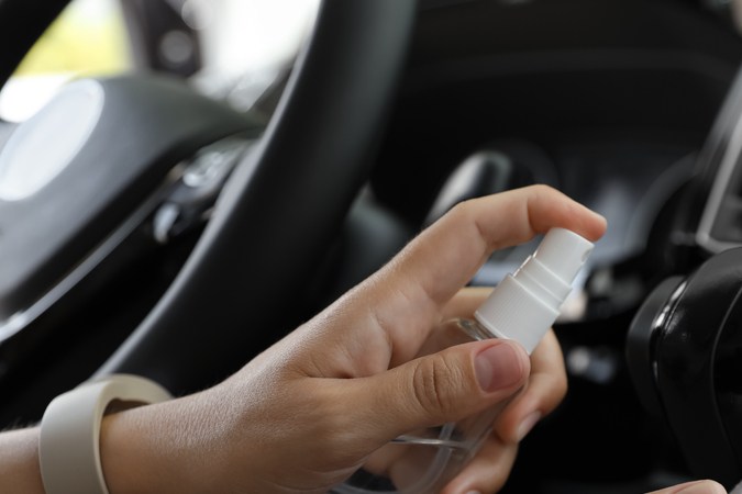Detalle de un spray casero siendo aplicado en el sistema de ventilación del vehículo.