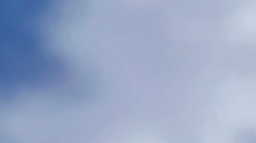 Primer plano del logotipo de Toyota en un automóvil híbrido rojo con reflejo del cielo