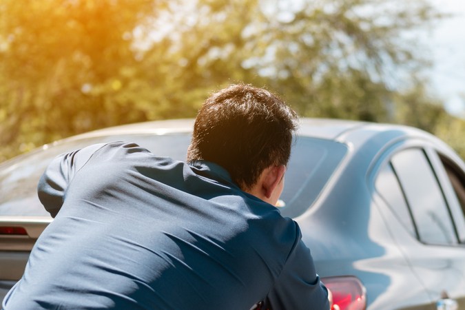 Persona empujando carro automático varado, mostrando error común que daña la transmisión.