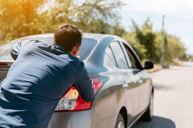 Persona empujando carro automático varado, mostrando error común que daña la transmisión.