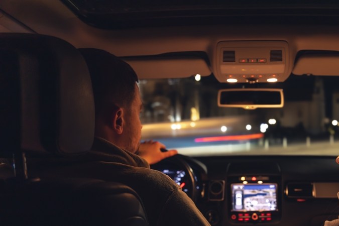 Un hombre y una mujer conducen en auto por la noche, desde el auto hasta la carretera.