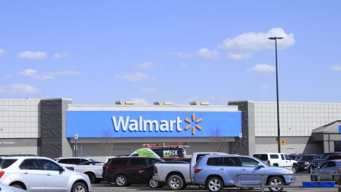 Una toma de una tienda Walmart con coches en el estacionamiento con cielo azul y nubes