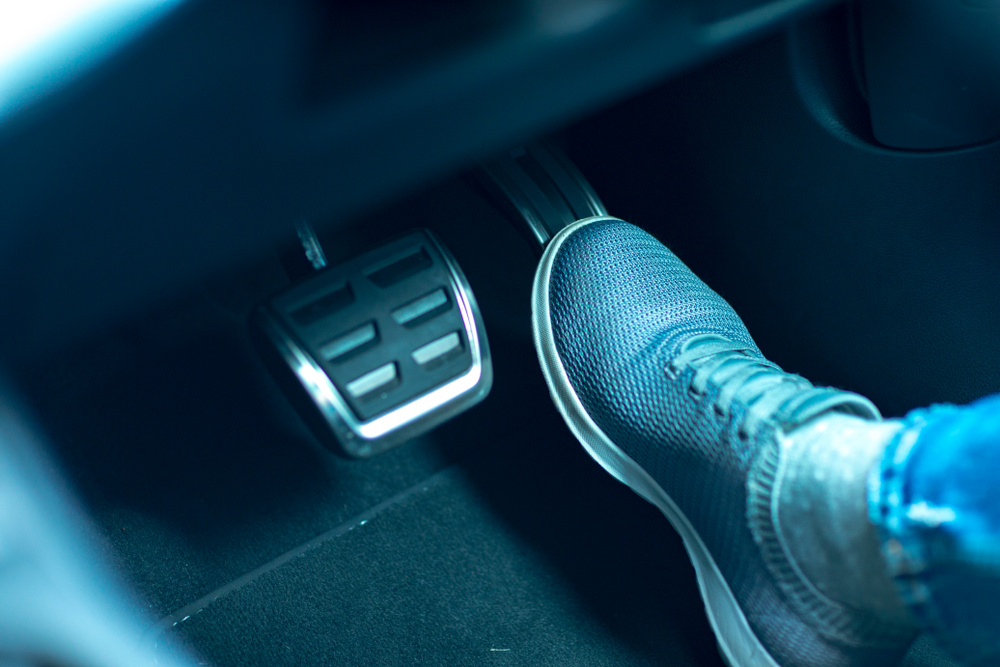 Pie en pedal de freno de auto, iluminación azul