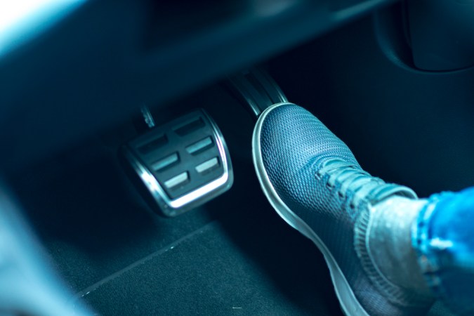 Pie en pedal de freno de auto, iluminación azul