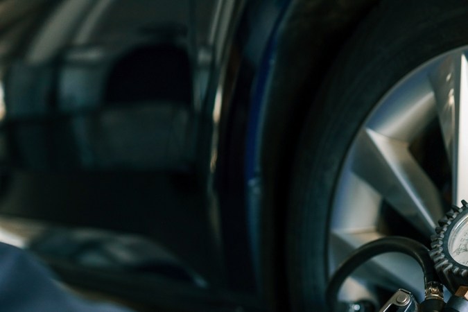 Un mecánico verifica la presión de los neumáticos con un medidor durante el mantenimiento rutinario del automóvil en un garaje.