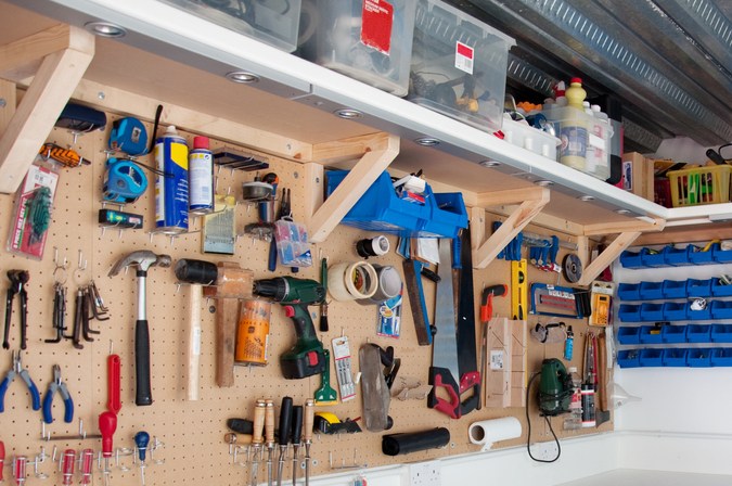 Garaje con estantes de madera y herramientas en pared ordenada.